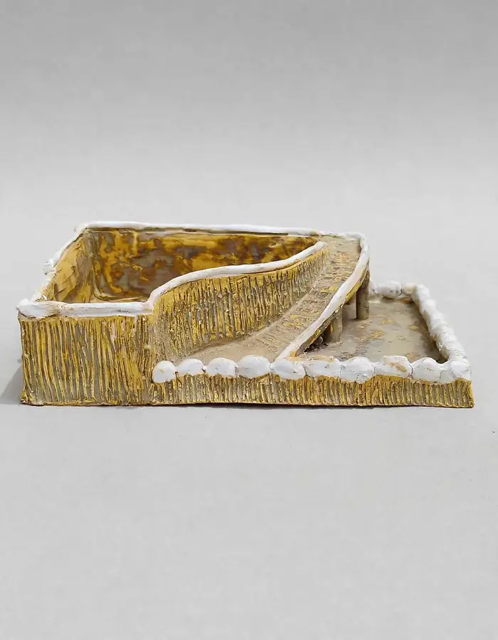 Small gilded ceramic diorama tray with a pillared walkway and white pebble border