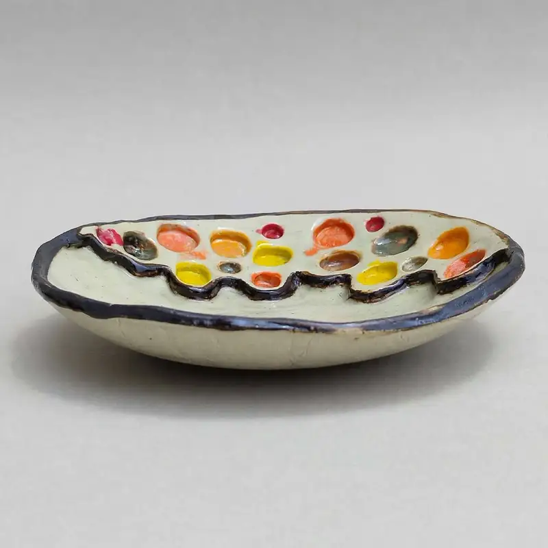 Oval ceramic dish with dark rim and pooled multicoloured glaze drops