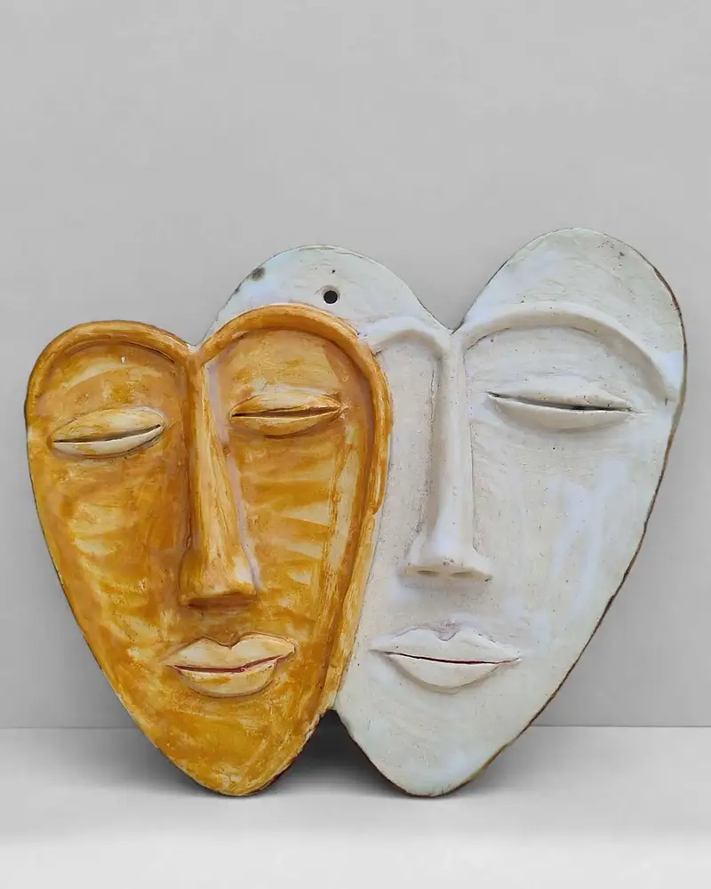 Heart-shaped ceramic face plaque glazed half mustard-yellow, half white